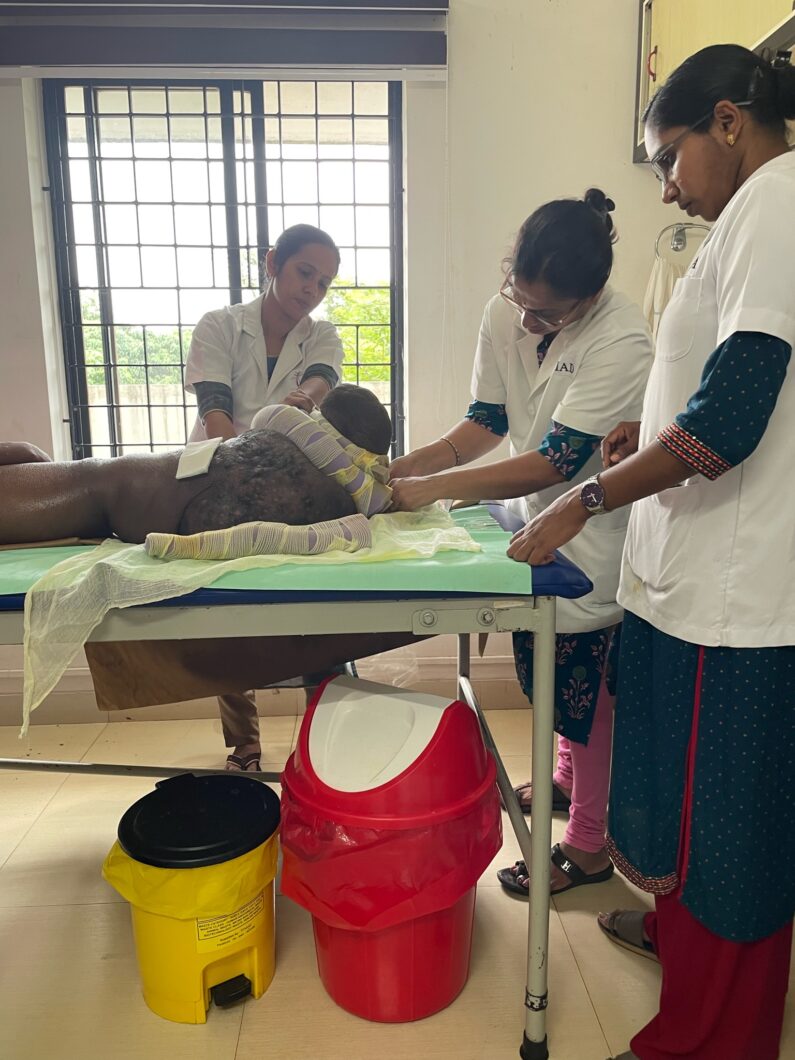 Three volunteers treat the foot of a patient with lymphoedema and lymphatic filariasis.