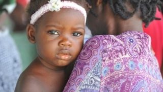 Haitianerin mit ihrem Baby auf dem Arm