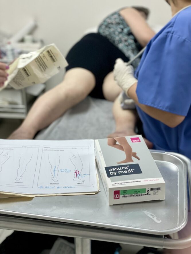 Eine Patientin wird in der Klinik von einer Helferin mit Kompressionsstrümpfen versorgt