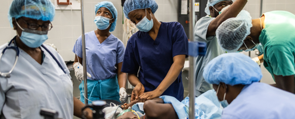 Ein junges Kind wird in einem Behandlungsraum von sechs Ärzten chirurgisch verorgt