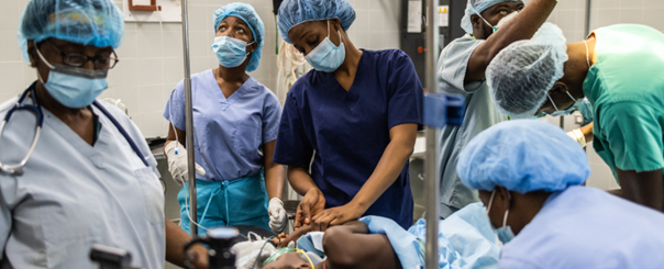 A young child is treated surgically by six doctors in a treatment room