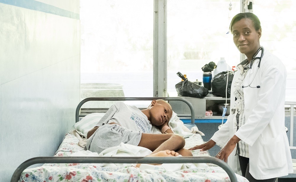 Im Behandlungsraum steht eine Ärztin am Bett des kleinen Jungen namens Lucien, welcher sein Bein gebrochen hat.