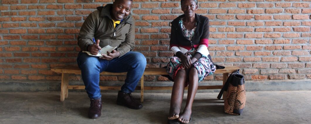 Compression Manager Jacques is sitting on the bench with a patient, smiling and taking notes