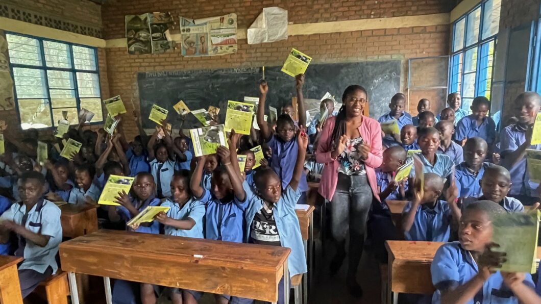 a school class full of children together with a teacher, all beaming with joy and raising their hands or applauding