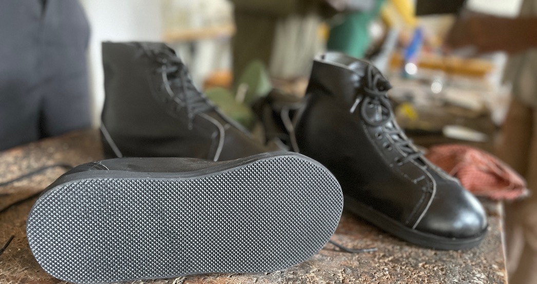 3 finished closed black shoes stand on a workbench