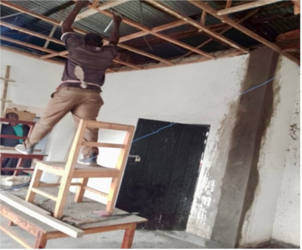 a helper carries out renovation work on the ceiling inside the rooms and holds a board